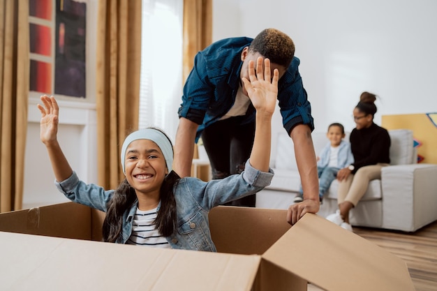 Little preschool girl sitting in boxes father rolling her real estate purchase concept