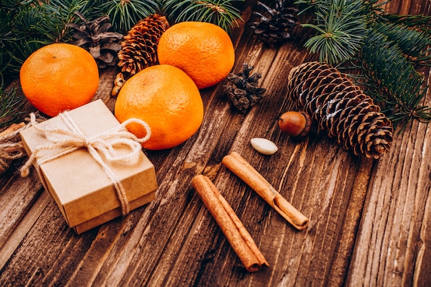 Little present box, species, tangerines and fir tree branch on a wooden table 