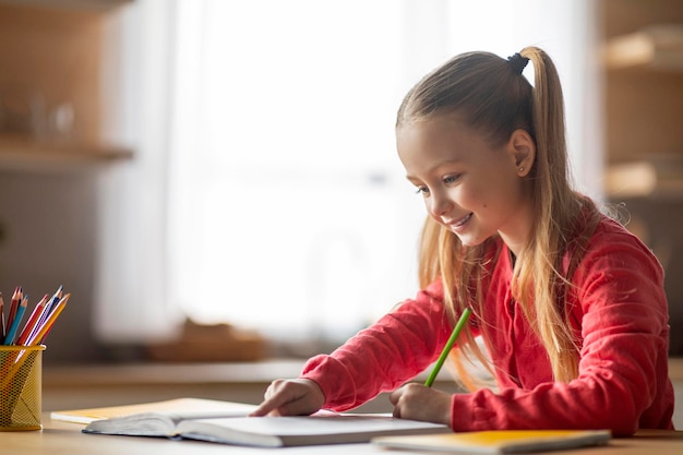 写真 家の机に座って学校の宿題をするプレティーンの少女