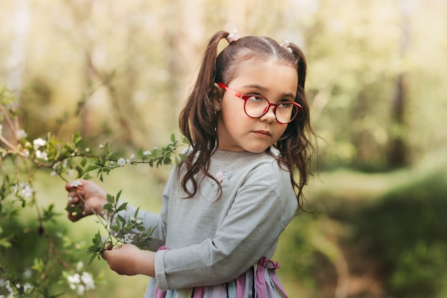 A little pretty girl holds a flower on a walk in the park in the summer on a sunny day