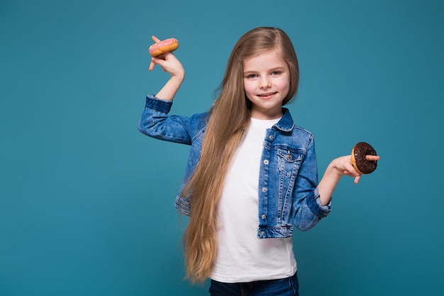 Piccola ragazza carina in giacca di jeans con lunghi capelli castani tenere pasta