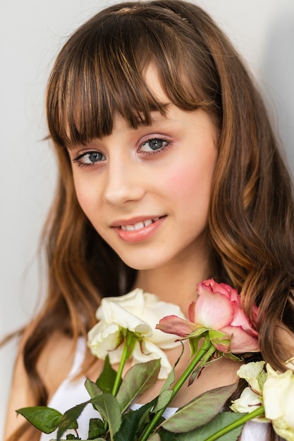 Little pretty girl in pink holds the bouquet of roses. Close up the flowers and face, little ballerina with a bouquet