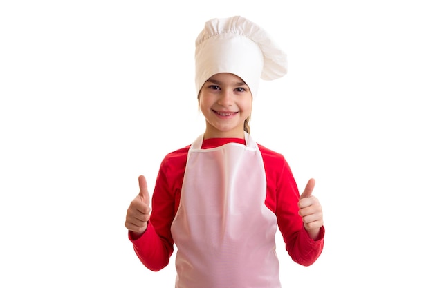 Little pretty girl in red shirt with white apron and hat holding rolling pin on white background