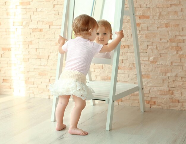 Little princess in beautiful dress posing near the mirror