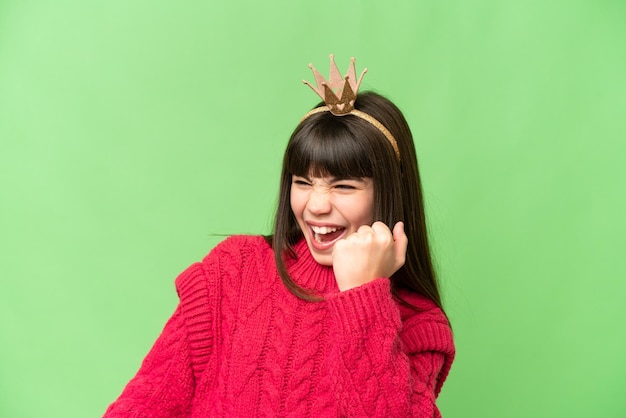 Little princess with crown over isolated chroma key background celebrating a victory