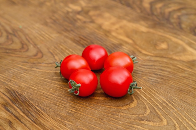 Little red cherry tomatoes on wooden board background Folded in a circle