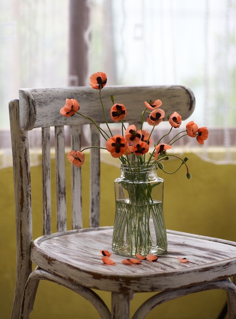 A Little Red Poppies Bouquet Arranged In Classical Style Stillife of popies in a glasses vase on vintage chair