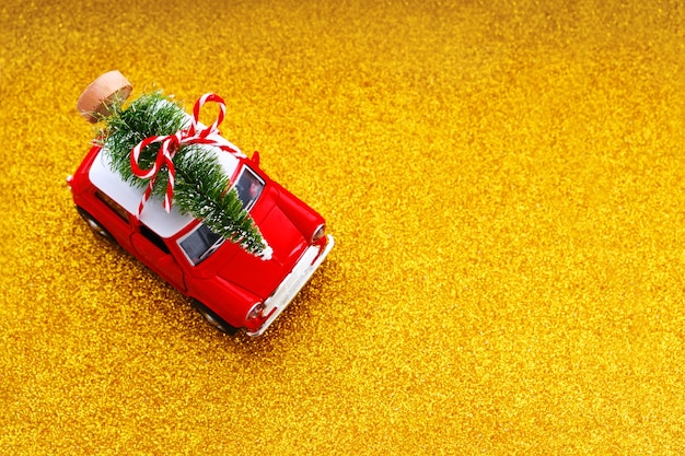 キラキラゴールドの小さな赤いおもちゃの車とクリスマスツリー。上面図