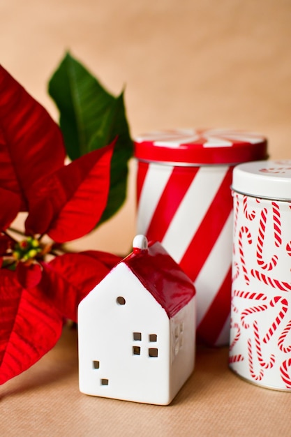 Little red and white toy house, poinsettia, two christmas tin boxes and craft paper background