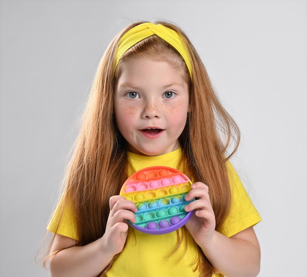 Little redhaired girl child with pop it showing surprised emotion