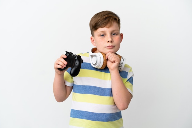 Little redhead boy holding a game pad isolated on white background and looking up