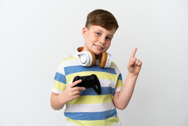 Little redhead boy holding a game pad isolated on white background showing and lifting a finger in sign of the best