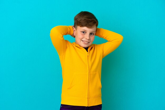 Little redhead boy isolated on blue background laughing