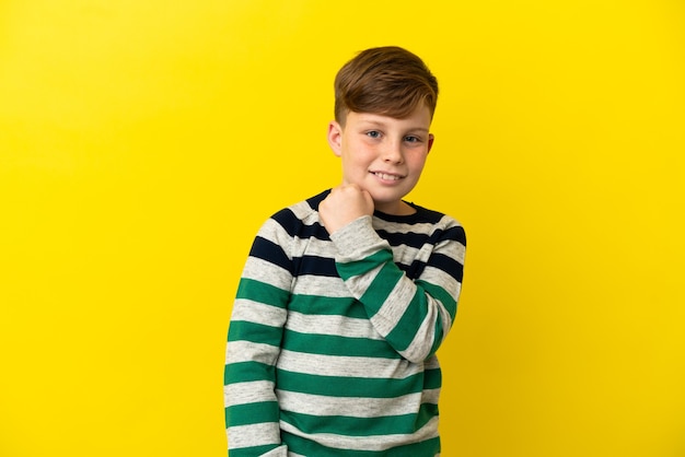 Little redhead boy isolated on yellow background celebrating a victory