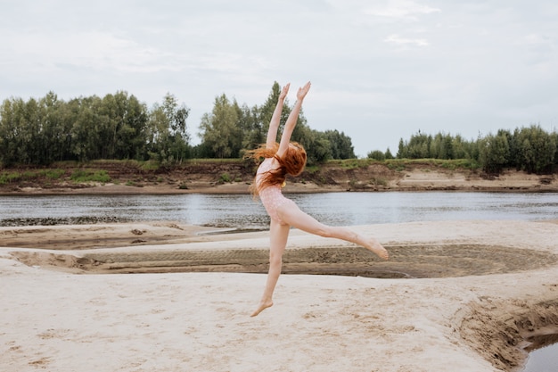 Little redhead girl playing on a beach