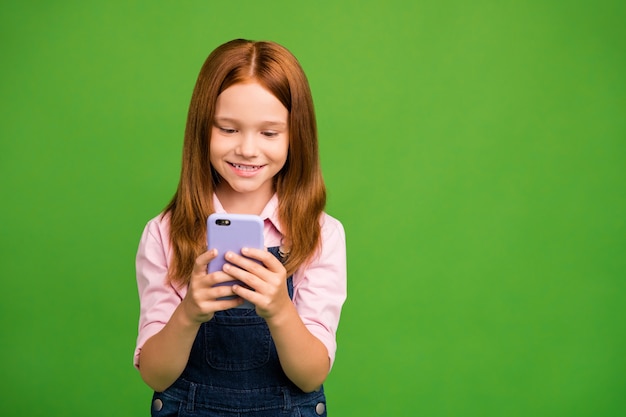 Little redhead girl posing against the green wall