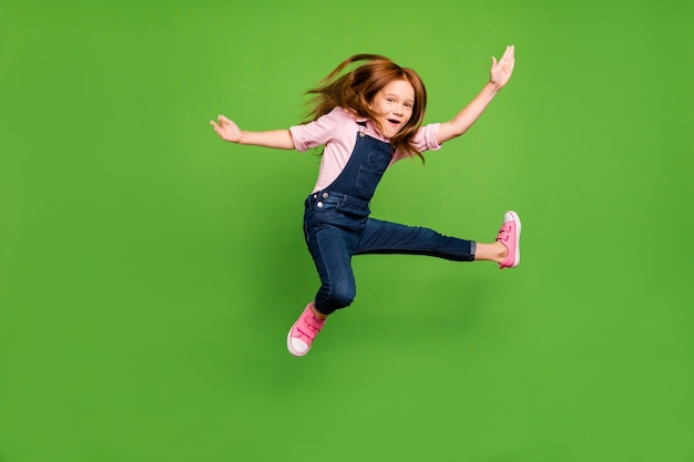 Little redhead girl posing against the green wall