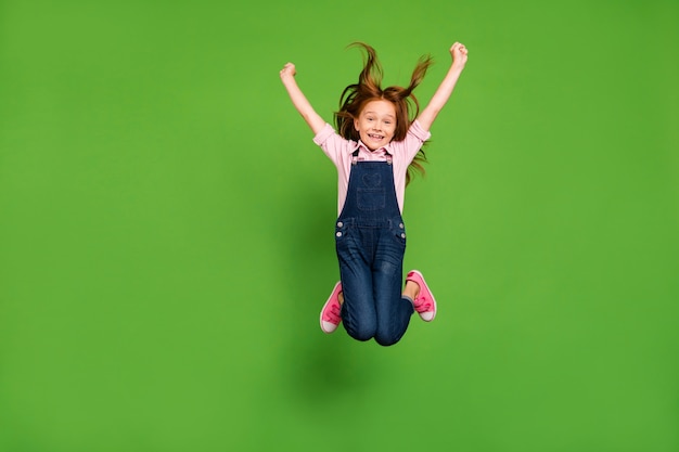 Little redhead girl posing against the green wall