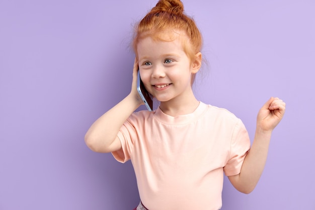 Little redhead girl talking on phone indoors