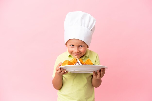 Little Russian boy holding waffles over isolated background