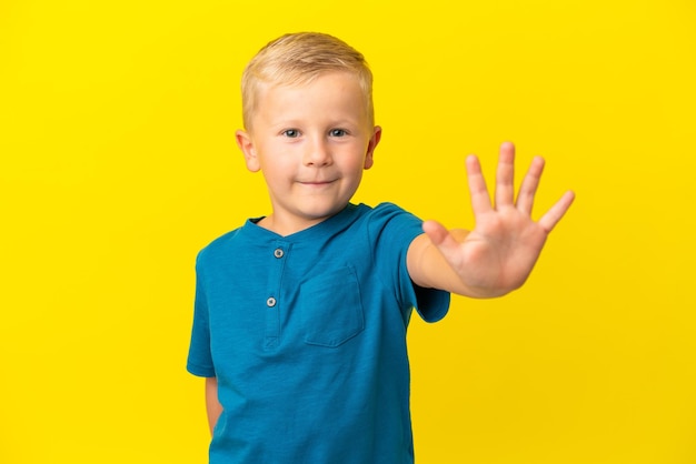 Little Russian boy isolated on yellow background counting five with fingers