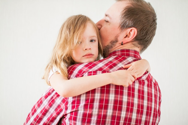 Foto piccola ragazza triste sulle braccia di papà. la figlia abbraccia papà.