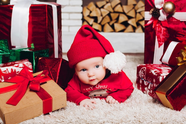 Маленький мальчик Санта лежит на полу в украшенном доме с рождественскими подарками