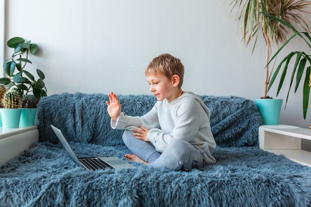 Little school boy having video call, online class on laptop  E-learning, distance studying, distance communication concept