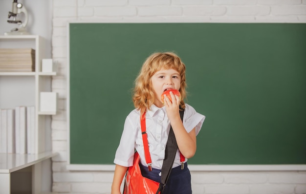 クラスでリンゴを食べる小さな男子生徒は、学校で英語を勉強します天才子供知識の日