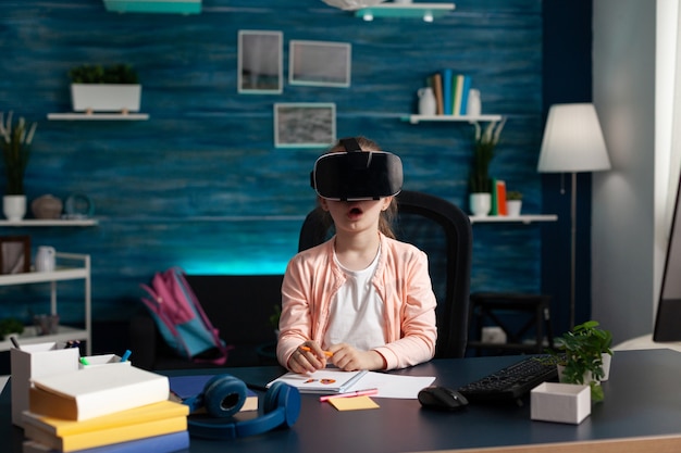 Little schoolchild wearing virtual reality headset enjoying playing with vr glasses