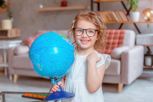 Little schoolgirl girl holding a globe