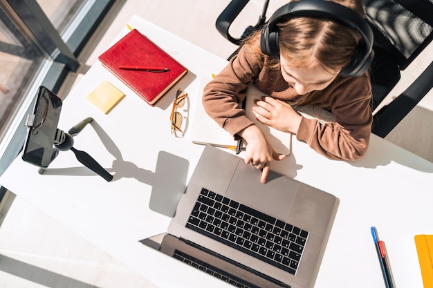 Little schoolgirl in headphones at computer