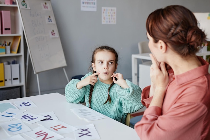 Photo little schoolgirl learning to read english words together with the teacher while they studying at desk in the classroom