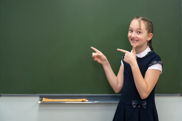 Little schoolgirl pointing to a chalkboard