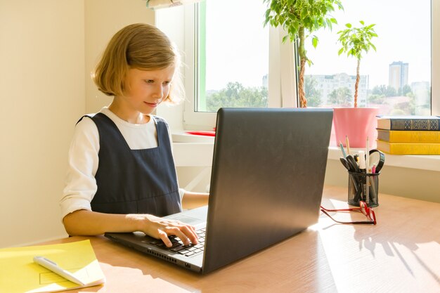 小さな女子高生はコンピューターのラップトップを使用します