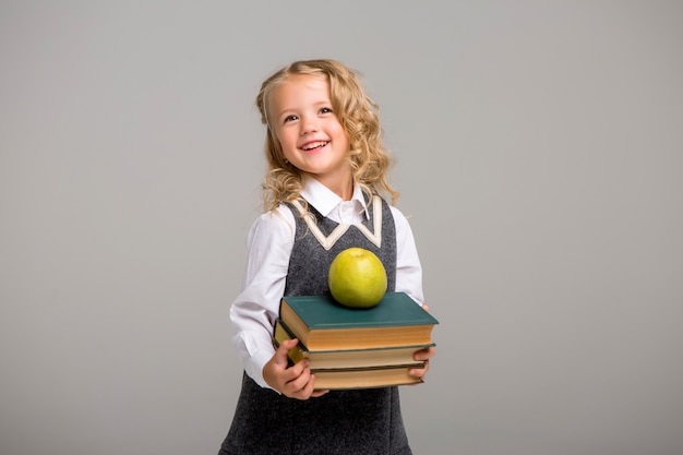 little schoolgirl with books on a light background