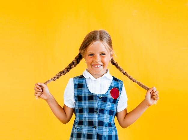 Little schoolgirl with a happy smile. Little schoolgirl in school uniform. 
