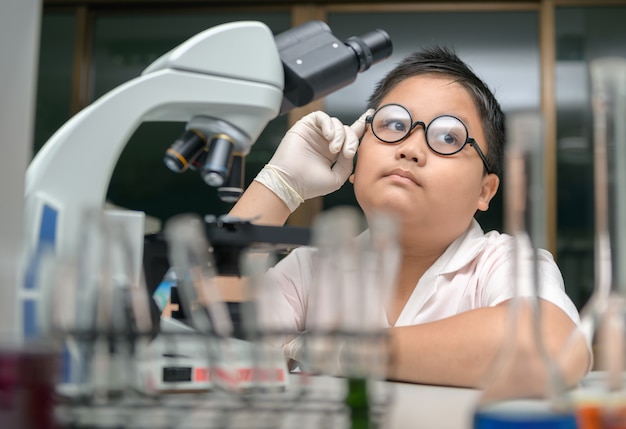 Little Scientist is sitting at the table and thinking at the laboratory