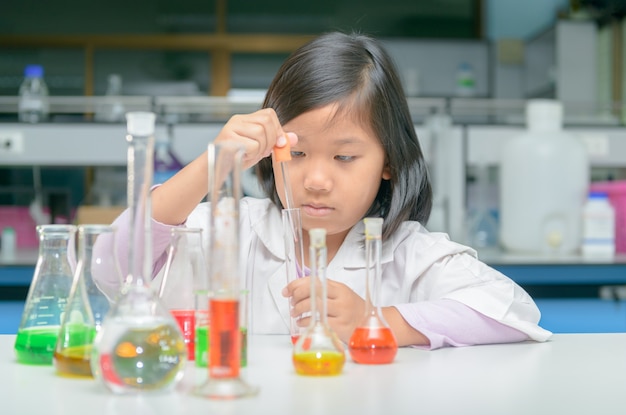 Little scientist in lab coat making experiment 