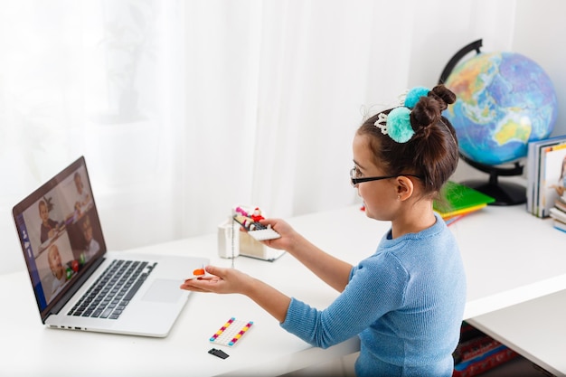 Little scientist working on new project, little girl studying robotics on laptop online