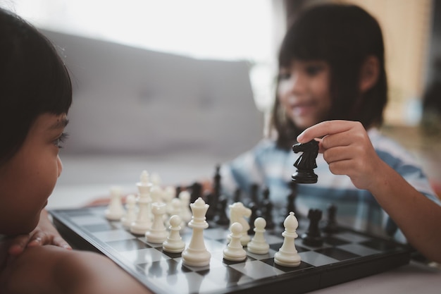 Little sibling girl playing chess at home.