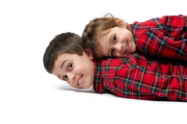 The little sister is lying on top of her brother Next to the boxes with gifts