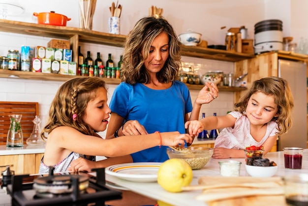 Little sisters cooking with her mother in the kitchen. Infant Chef Concept.