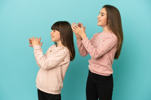 Little sisters girls isolated on blue background applauding after presentation in a conference