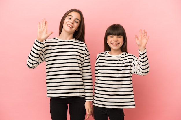 Little sisters girls isolated saluting with hand with happy expression