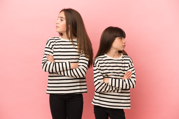 Photo little sisters girls isolated with confuse face expression while bites lip