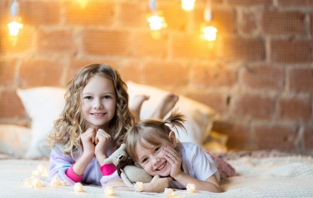 Little sisters in pajamas on the bed