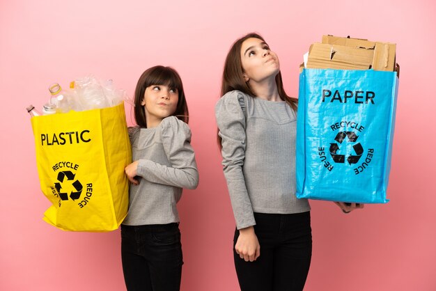 分離された紙とプラスチックをリサイクルする妹たちが、肩を上げながら疑いのジェスチャーをする