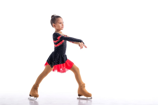 Little skater posing in red and black dress on ice isolated on white background