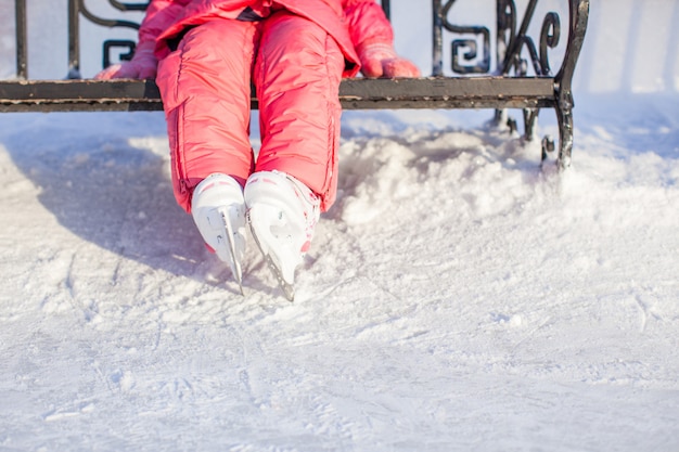 Le gambe del piccolo pattinatore che stanno sulla pista di pattinaggio sul ghiaccio di inverno